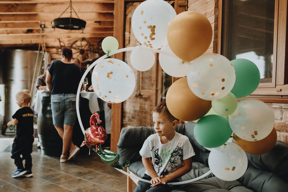 Crianças celebrando uma festa infantil com balões decorativos em ambiente acolhedor e rústico.