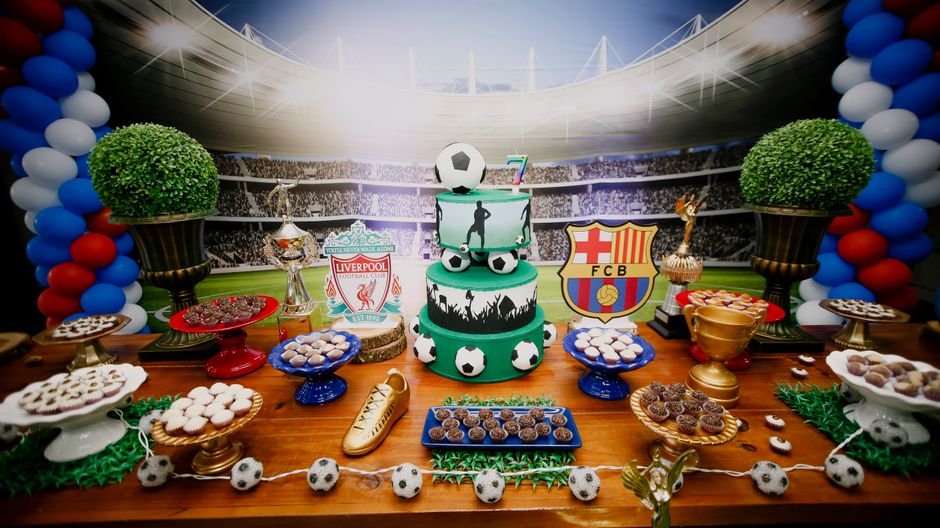 Decoração de festa com tema de futebol, destacando bolo temático, troféus e simbolismos do esporte em um ambiente festivo esportivo.