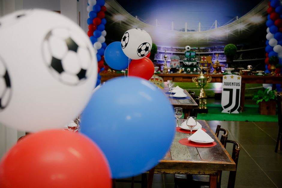 Decoração de festa infantil com tema de futebol, os detalhes incluem balões coloridos com estampas de bola e elementos relacionados ao esporte.