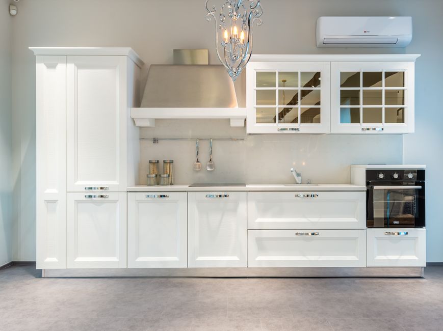Cozinha moderna com armários brancos, fogão embutido e detalhes elegantes que destacam o design clean e funcionalidade do espaço.