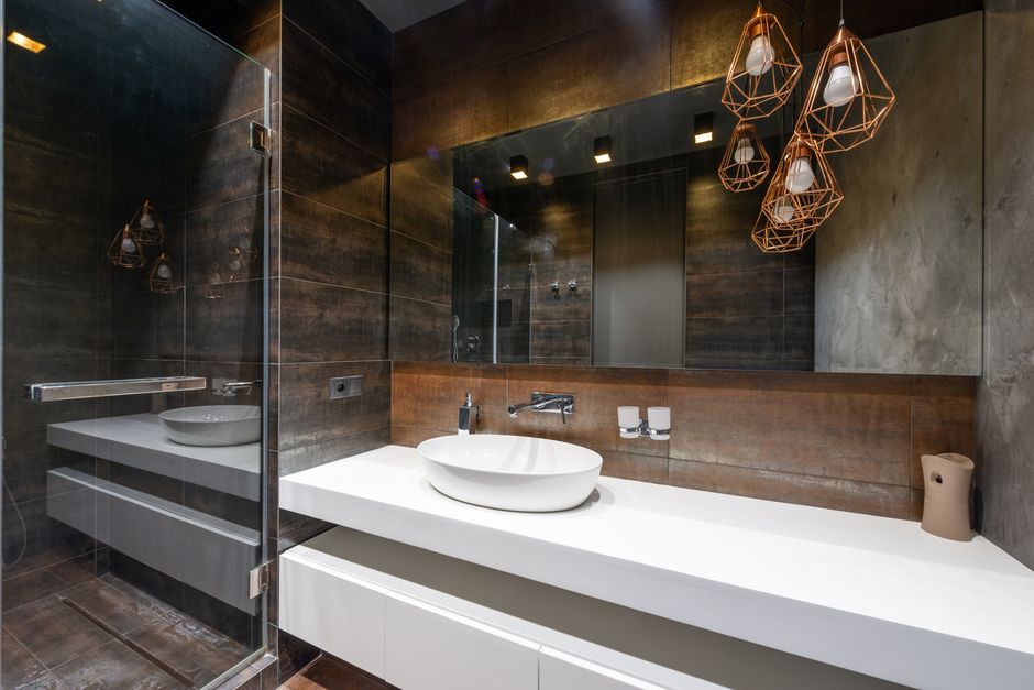 Banheiro moderno com acabamento rústico e iluminação de design, ideal para blogs de decoração de interiores ou tendências em arquitetura.