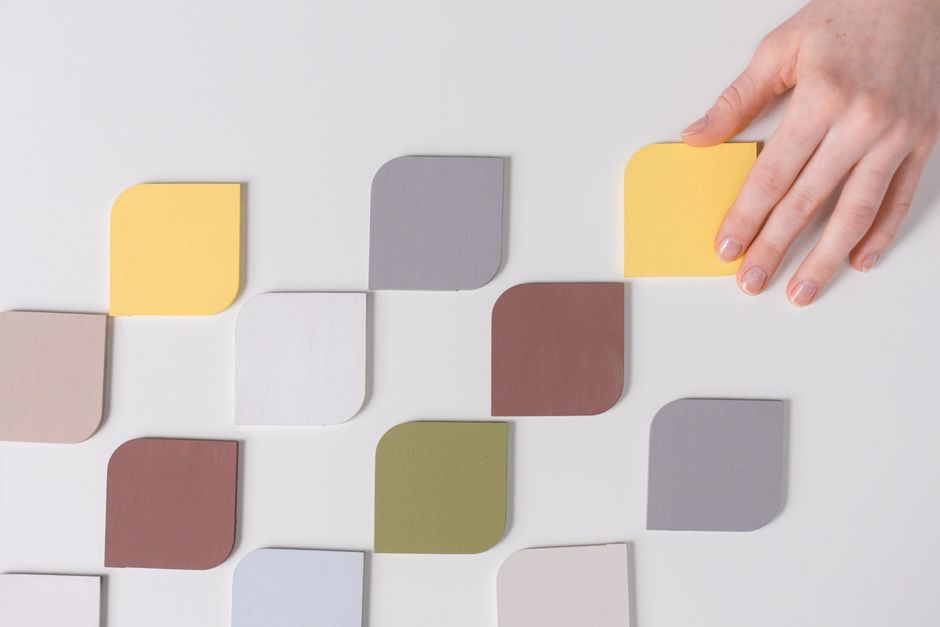 Imagem de peças de madeira coloridas sendo organizadas por uma mão, simbolizando criatividade, organização e design de ambientes modernos.