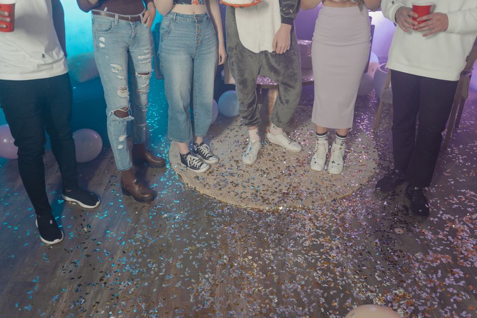 Grupo de amigos celebrando uma ocasião especial com confetes e balões coloridos em um ambiente festivo.