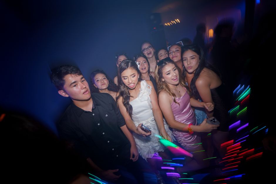 Grupo de jovens em uma festa animada, capturando momentos de diversão e socialização em ambiente de clube ou evento social.