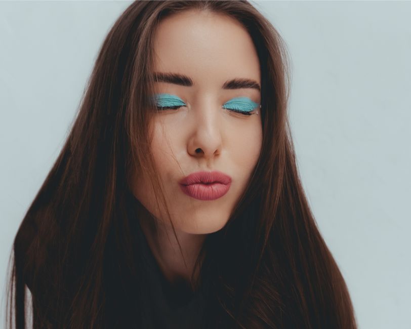 Uma mulher com maquiagem marcante e expressão de descanso, transmitindo beleza e autoexpressão em um retrato de moda ou beleza.