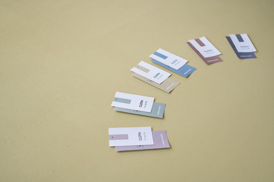 Imagem de diversas amostras de cores para tecidos, organizada em uma linha sobre fundo bege, ideal para ilustrar escolha de cores na moda ou design de interiores.
