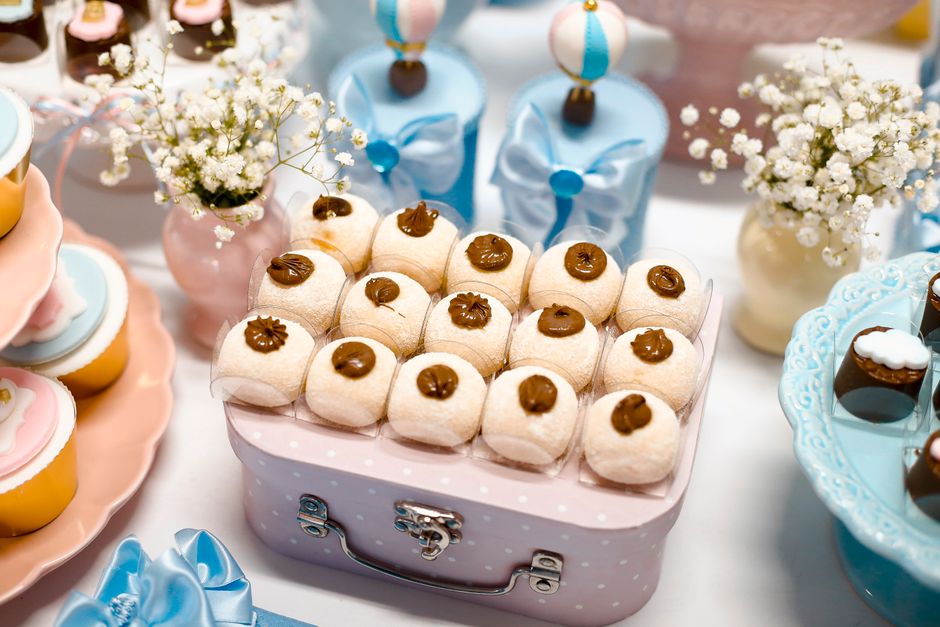 Mesa decorada com doces finos, flores e detalhes delicados, ideal para comemoração infantil ou casamento.