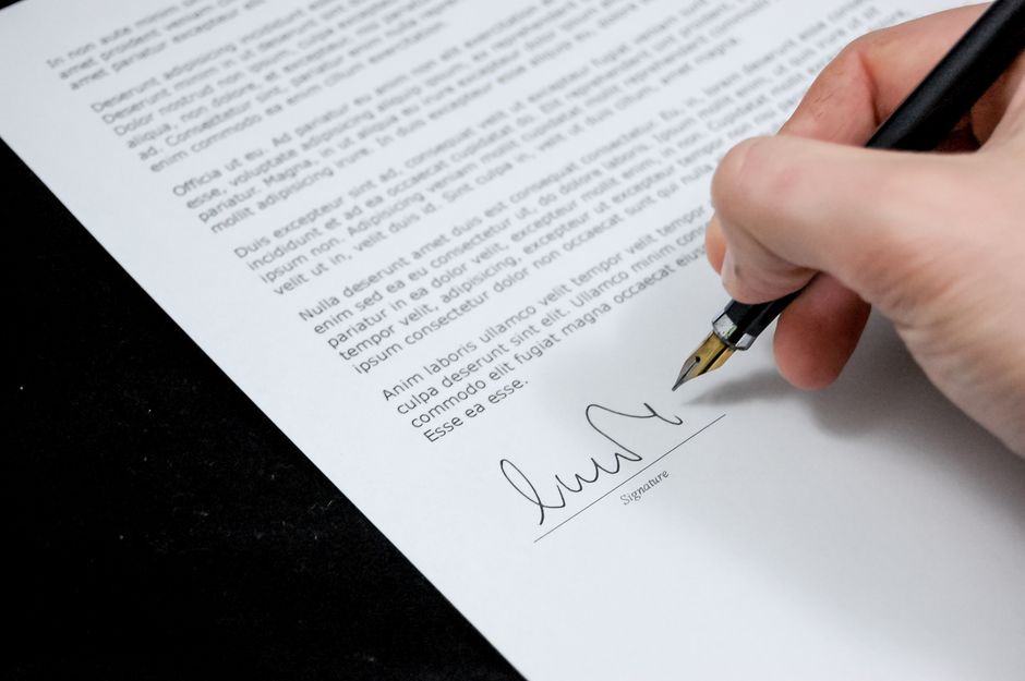Pessoa assinando um documento importante, simbolizando formalização ou contrato.