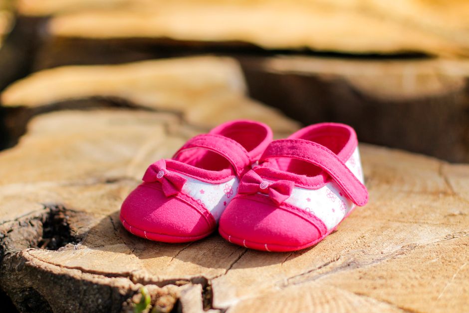 Par de sapatinhos de bebê rosa sobre uma superfície de madeira, simbolizando crescimento e novos começos.