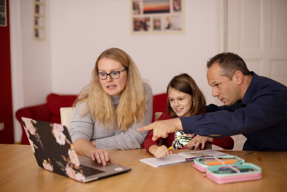 Família discutindo planejamento escolar ou atividades pedagógicas em casa, com foco na educação infantil.