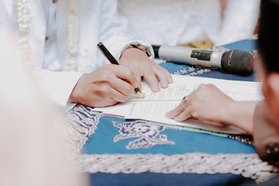 Pessoa assinando um documento importante em um ambiente formal, possivelmente em um evento ou cerimônia de assinatura.