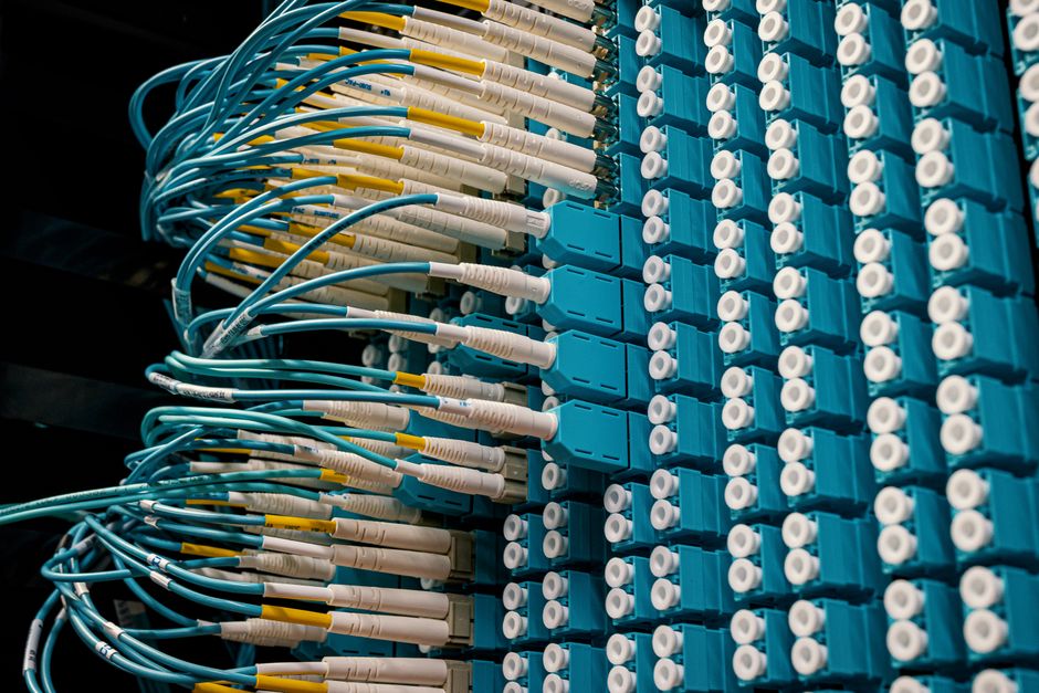 Imagem de um painel de fibra óptica organizado, representando conectividade e infraestrutura de tecnologia da informação.