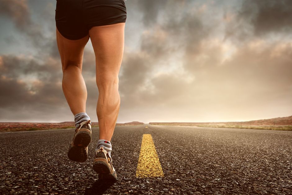 Homem ou mulher caminhando ou correndo na estrada ao entardecer, simbolizando jornada, perseverança ou metas de fitness.