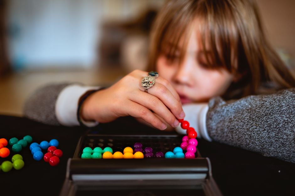Mulher jogando um jogo de tabuleiro com bolas coloridas, destacando o tema de lazer e diversão.