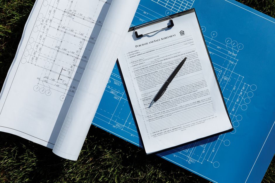 Imagem de um contrato de compra e venda sobreposto a planos arquitetônicos, simbolizando negócios e planejamento de obras.