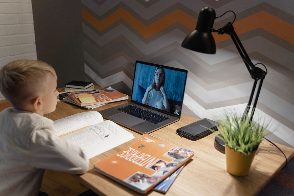 Criança estudando com aula virtual em um ambiente de casa, demonstrando o uso de tecnologia na educação infantil.