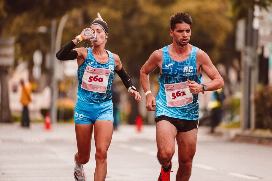 Duas pessoas participando de uma corrida de rua, mostrando esforço e dedicação ao esporte.