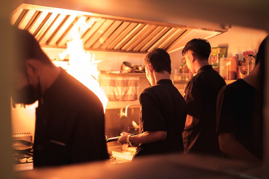 Equipe de chefs preparando pratos em uma cozinha profissional durante o turno de jantar.