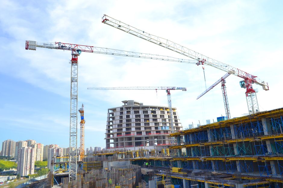 Imagem de um conjunto de edifícios em construção com várias torres de andaime e plataformas, destacando um canteiro de obras em fase de crescimento urbano.