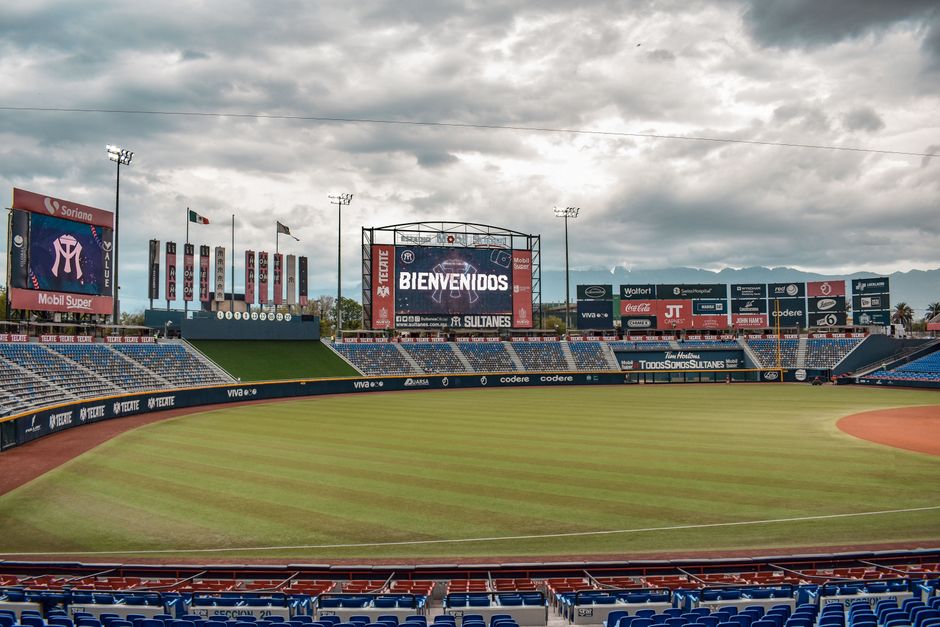 Estádio de beisebol vazio com céu nublado, preparado para um jogo ou evento esportivo.
