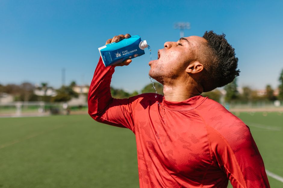 Atleta hidratando-se após treino ou jogo ao ar livre, simbolizando cuidado com saúde e desempenho esportivo.