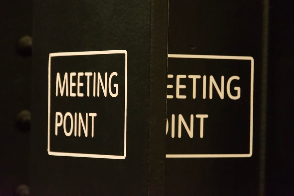 Placa indicando o ponto de encontro para reuniões empresariais, simbolizando organização e planejamento corporativo.