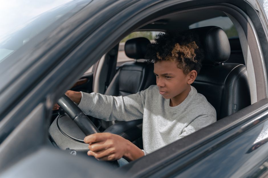 Jovem dirigindo um carro, representando o tema de educação no trânsito e segurança viária.