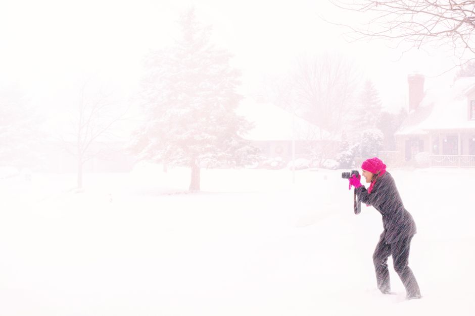 Mulher com roupa de inverno fotografando uma paisagem coberta de neve em um cenário aconchegante de inverno.