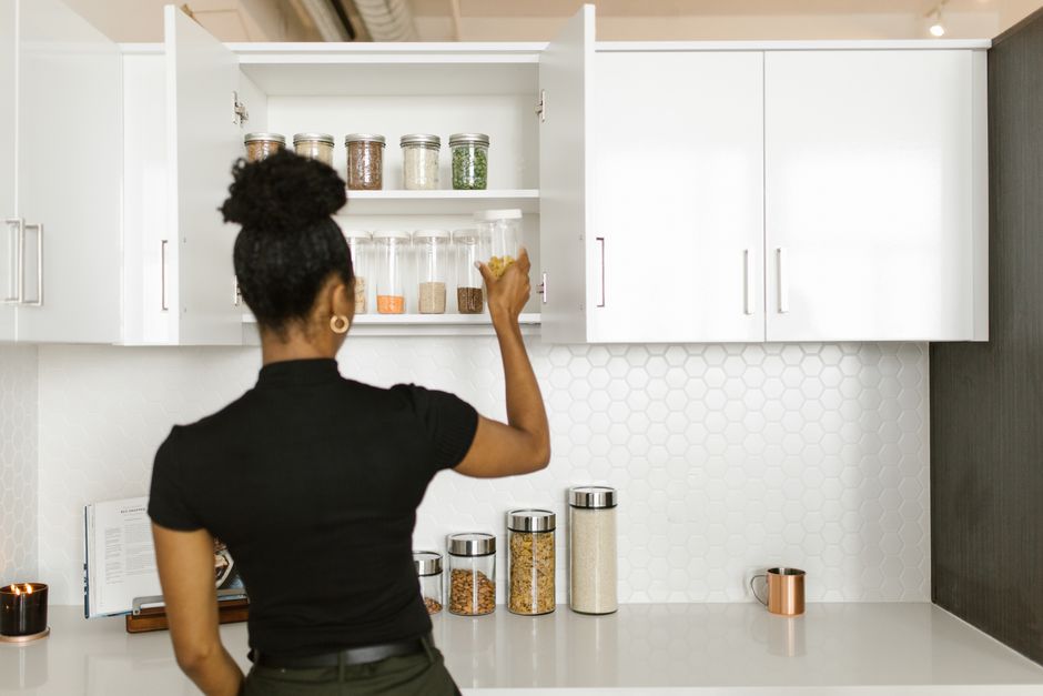 Mulher organizando e armazenando alimentos em uma cozinha moderna, enfatizando o tema de organização doméstica e alimentação saudável.