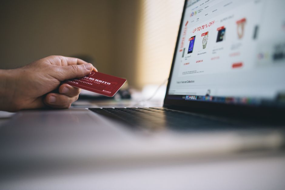 Pessoa realizando compra online com cartão de crédito em laptop, destacando tendências de e-commerce e pagamentos digitais.