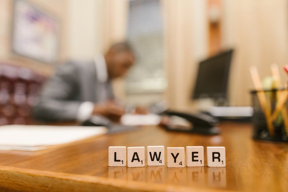 Imagem de um escritório com foco na palavra 'LAWYER' formada por cubos de madeira, indicando advocacia ou serviços jurídicos.