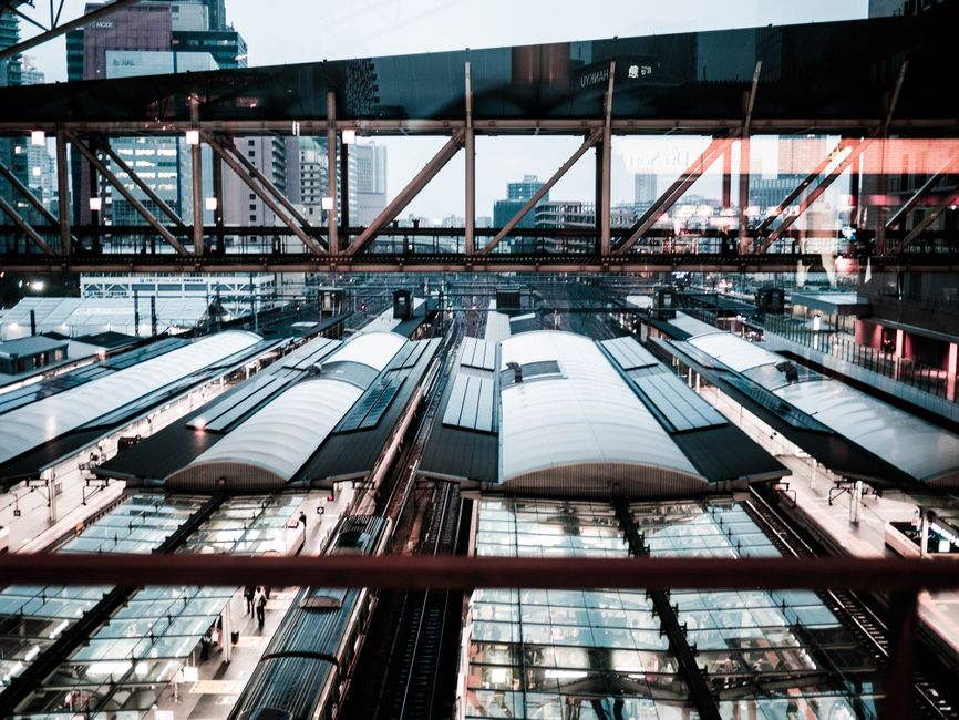 Imagem de uma estação de metrô moderna no centro de uma cidade grande, com edifícios altos ao fundo, transmitindo a ideia de mobilidade urbana e transporte público eficiente.