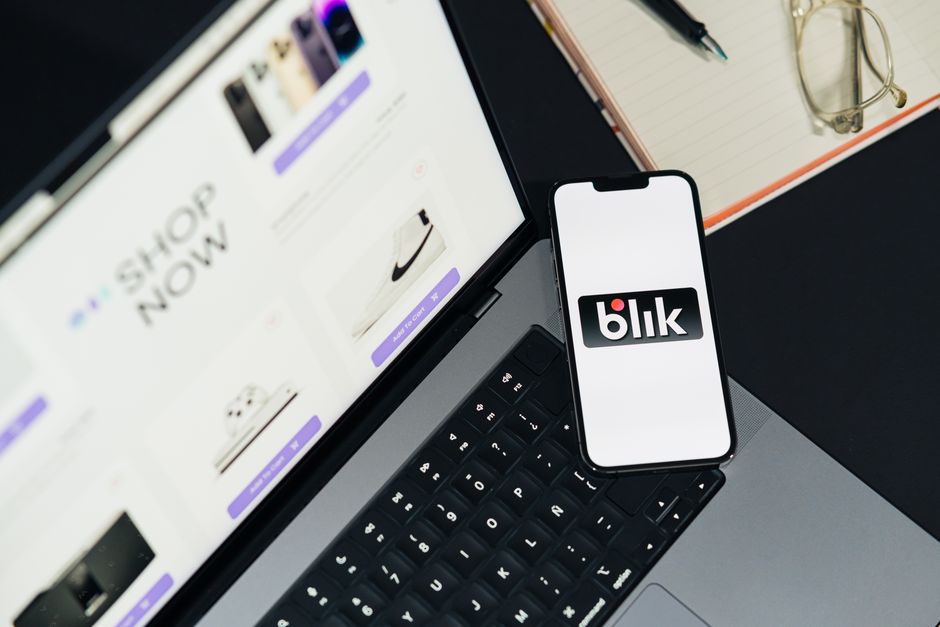 Imagem de uma estação de trabalho com um laptop, um smartphone exibindo o logo da plataforma blik, e itens de escritório, simbolizando tecnologia e gestão digital.