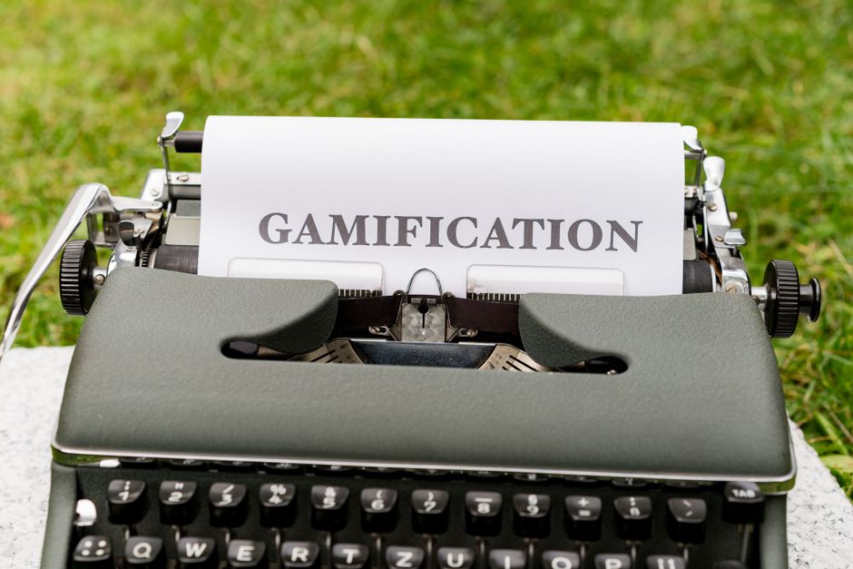 Máquina de escrever com a palavra 'Gamification' impressa em papel, simbolizando inovação e engajamento em ambientes educacionais ou corporativos.
