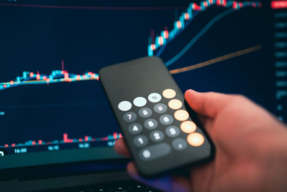 Imagem de uma pessoa segurando um smartphone com um gráfico financeiro de ações ao fundo, destacando temas de análise de investimentos e mercado financeiro.