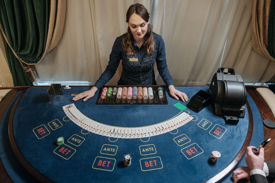 Mulher atuando como crupiê em mesa de caça-nóqueis, demonstrando jogo de apostas e estratégia de apostas em um ambiente de cassino.