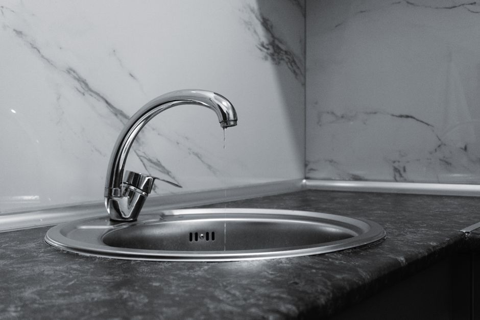 Imagem de uma cozinha moderna com cuba de pia de aço inox e torneira, destacando um ambiente limpo e sofisticado.