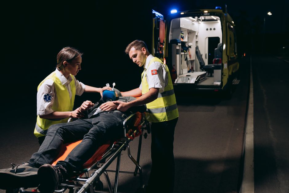 Equipe de profissionais prestando atendimento de emergência a um paciente em uma ambulância durante a noite.