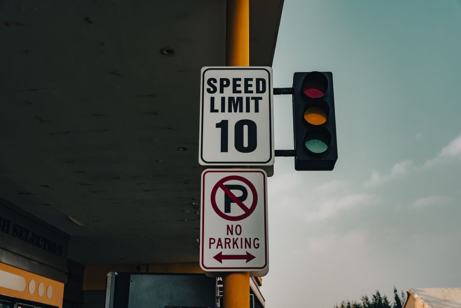 Sinalização de limite de velocidade e proibido estacionar em uma rua, destacando aspectos de segurança viária.