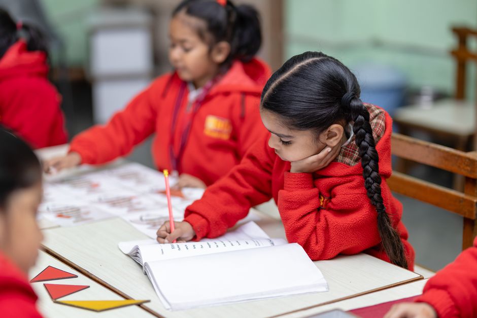 Crianças estudando na turma de uma escola, centradas na atividade escolar em ambiente educacional.