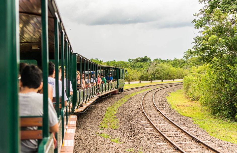Pessoas aproveitando um passeio de trem ao ar livre em um ambiente natural, explorando a experiência de turismo ecológico.