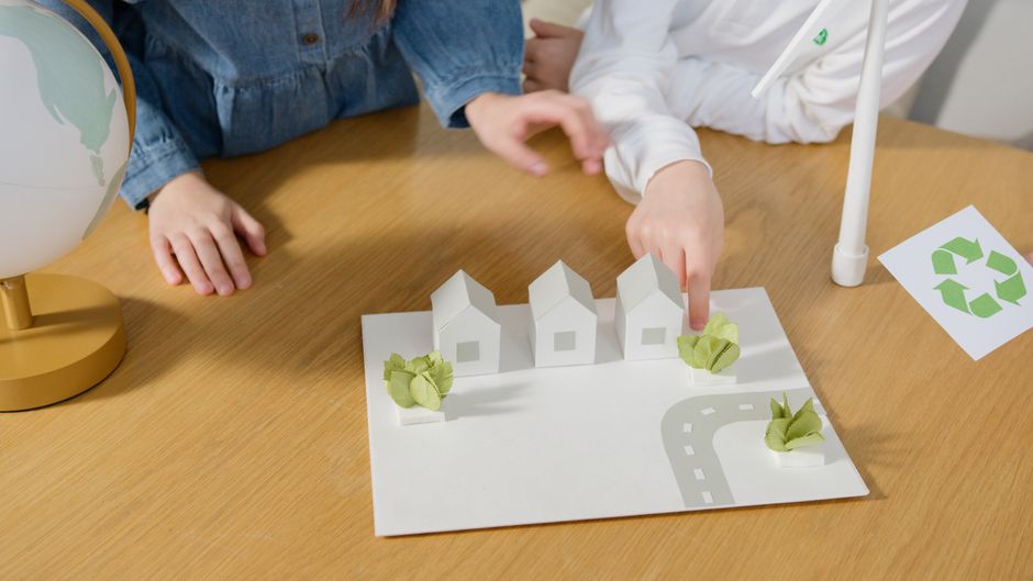 Duas crianças explorando um modelo de bairro sustentável com foco em planejamento urbano e meio ambiente.