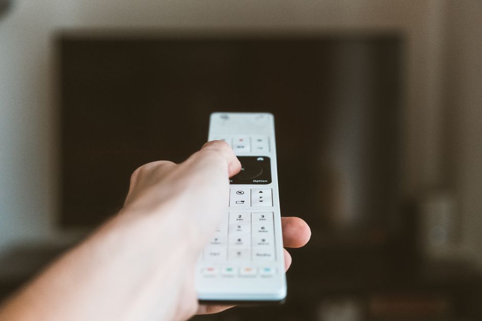 Pessoa utilizando um controle remoto em um ambiente doméstico, sugerindo controle e automação de dispositivos eletrônicos.