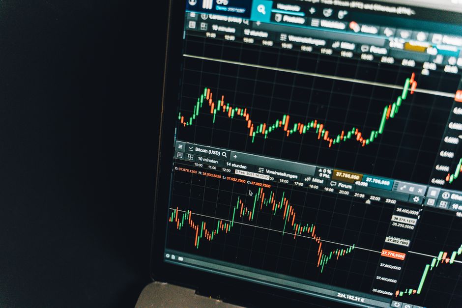 Imagem de um monitor exibindo gráficos de análise de mercado financeiro e criptomoedas, ilustrando tendências e variações em investimentos digitais.