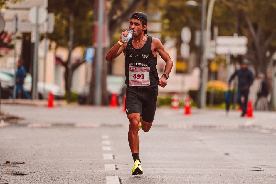 Atleta participando de uma corrida de rua, demonstrando esforço e resistência em um evento esportivo ao ar livre.