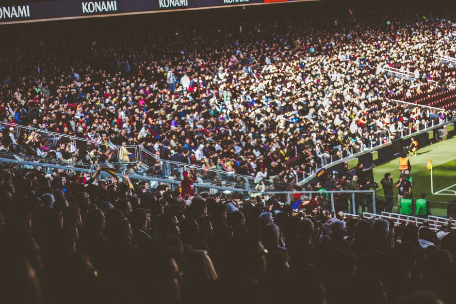 Multiplicidade de espectadores em um estádio de futebol durante uma partida, evidenciando o interesse esportivo em grande escala.