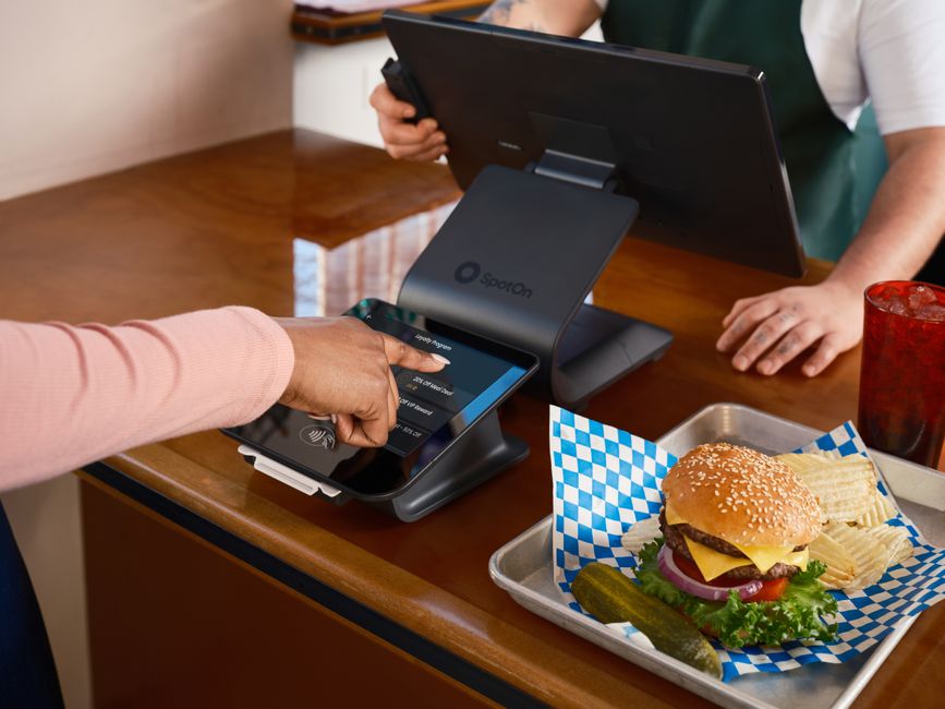 Pessoa realizando pagamento digital em restaurante, destacando tecnologia de ponto de venda e pagamento sem contato.