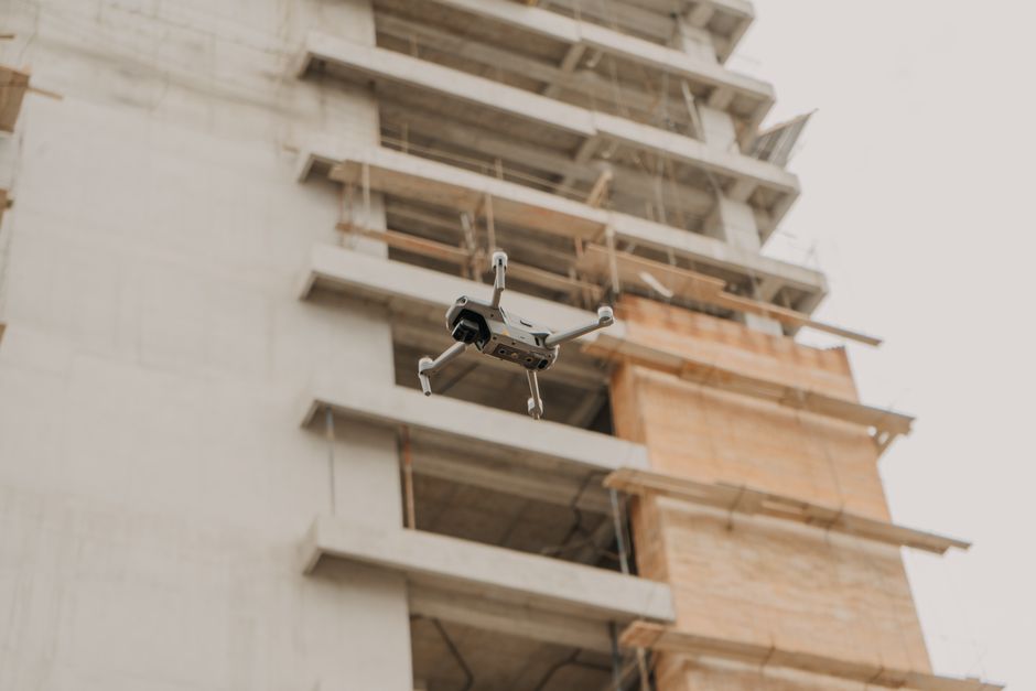 Drone capturando imagens de um edifício em construção, simbolizando tecnologia na construção civil.