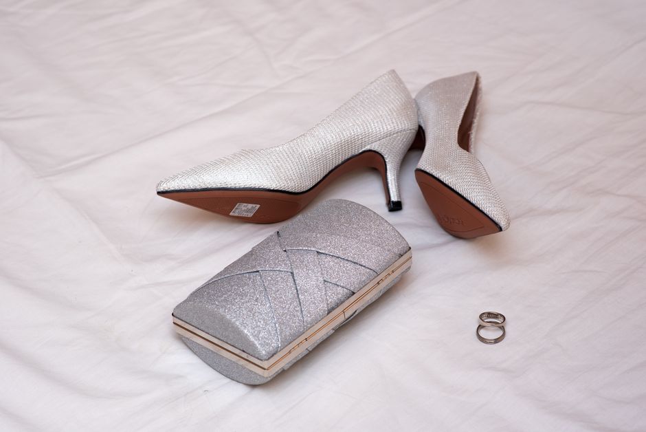 Imagem de acessórios de moda femininos com sapatilha de salto, carteira glamourosa e anéis, sugerindo elegância e estilo para ocasiões especiais.