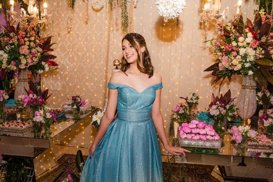 Jovem vestida de vestido azul deslumbrante em celebração com decoração de flores e luzes, ideal para um evento social ou festa temática.